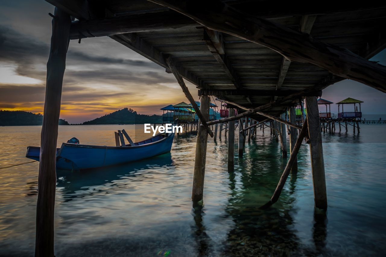 Boats moored in sea against sky during sunset