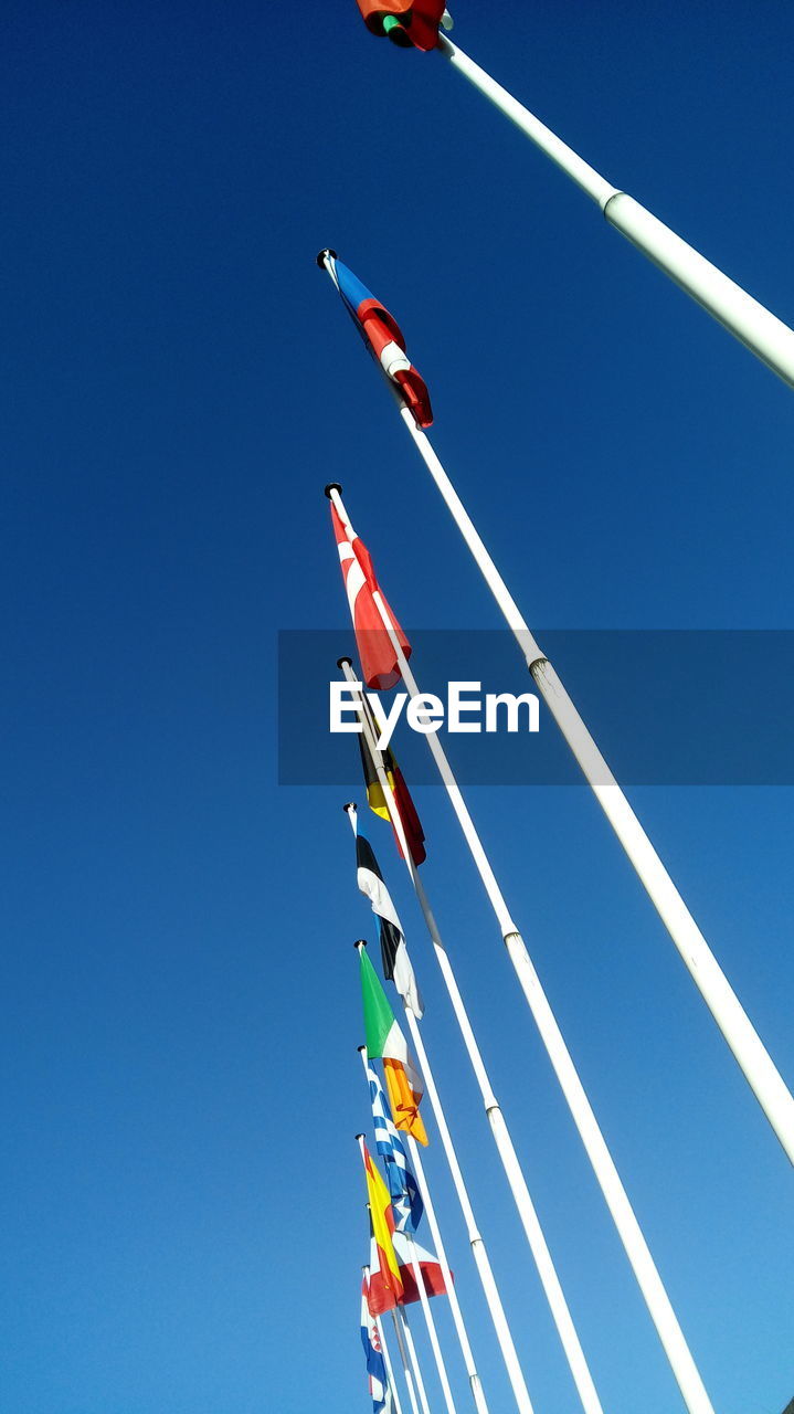 LOW ANGLE VIEW OF FLAG HANGING AGAINST CLEAR BLUE SKY