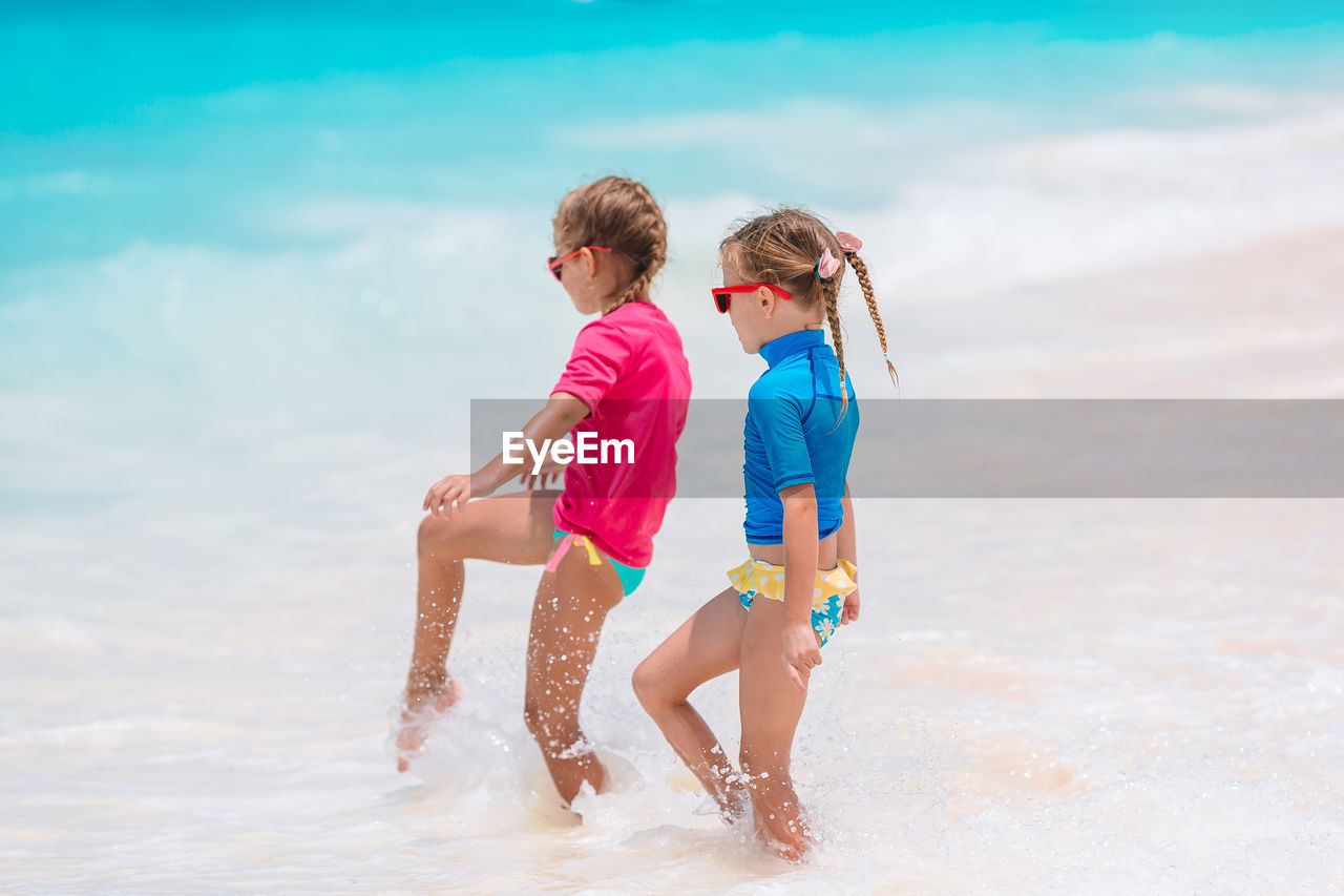 Siblings at beach against sky