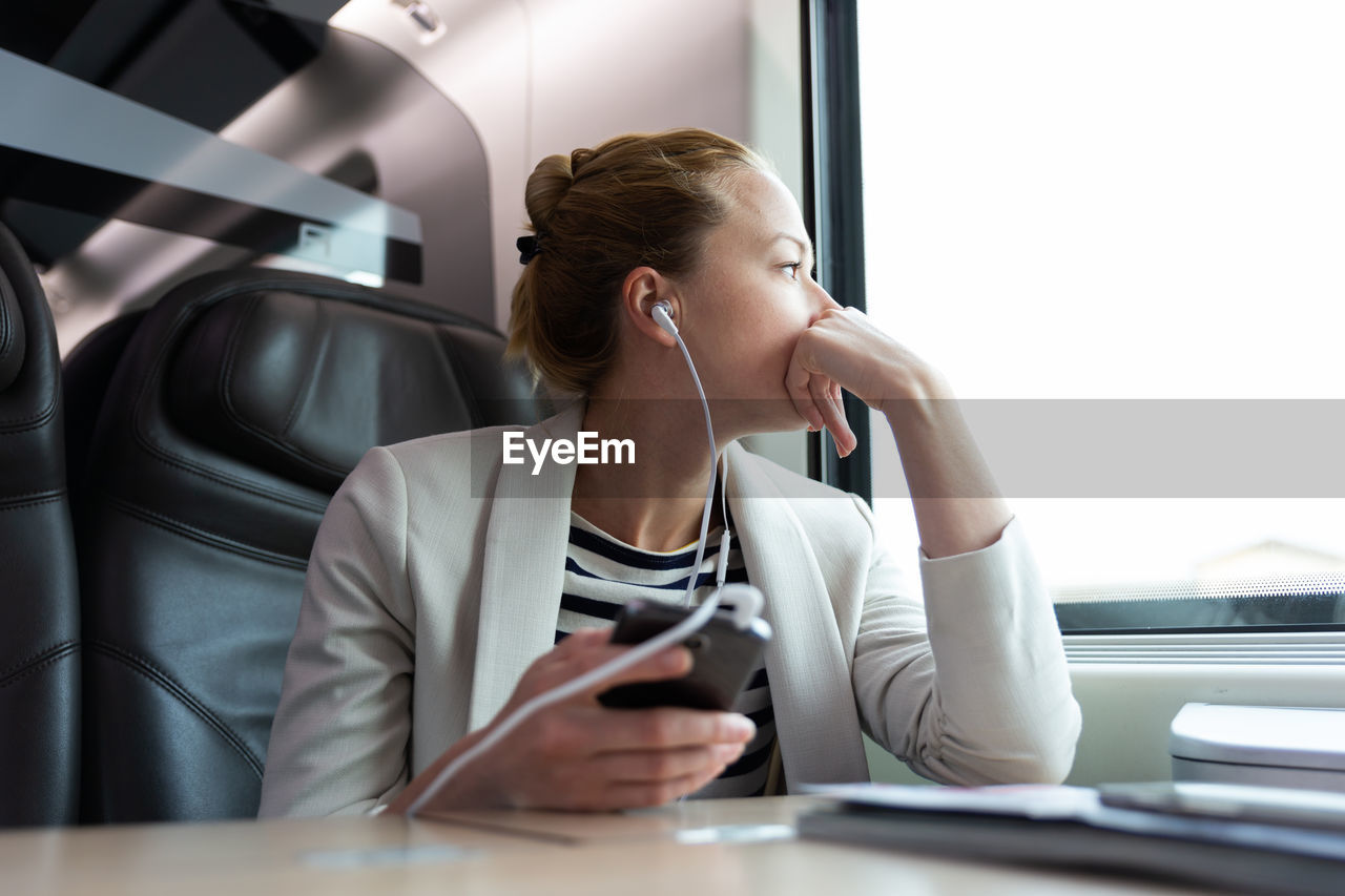 Young woman using mobile phone while sitting in bus