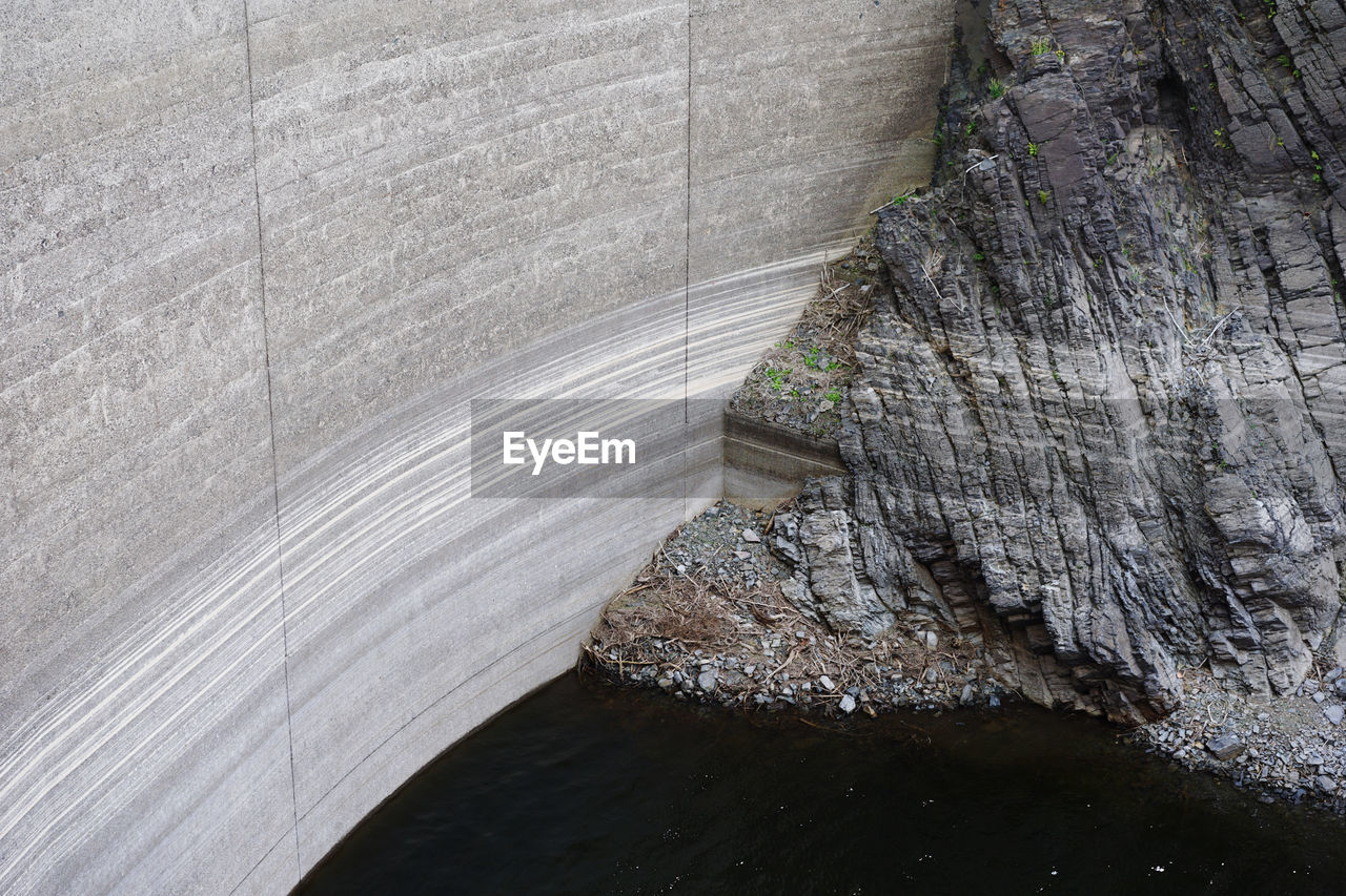 High angle view of water in a dam, with the dam wall and rocks showing water evaporation levels