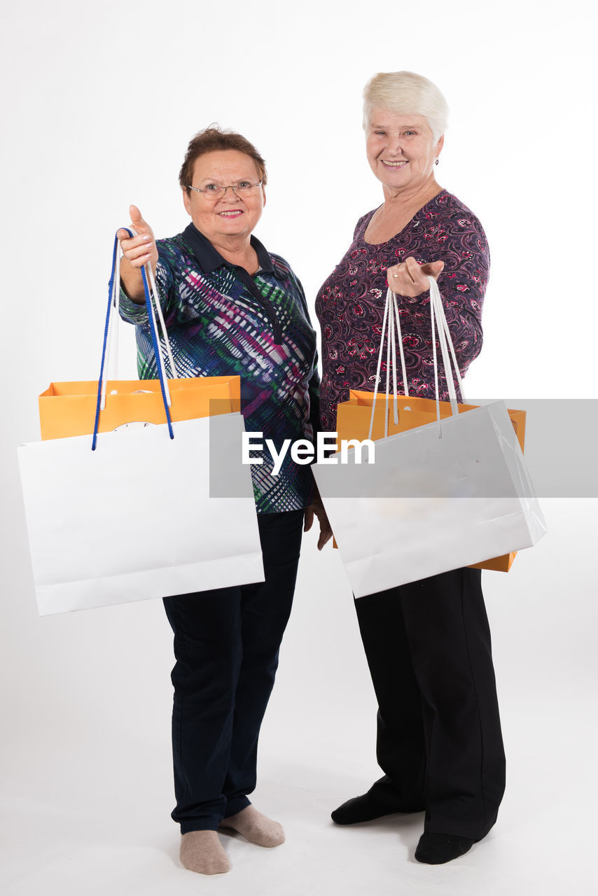 Friends with shopping bags standing against white background