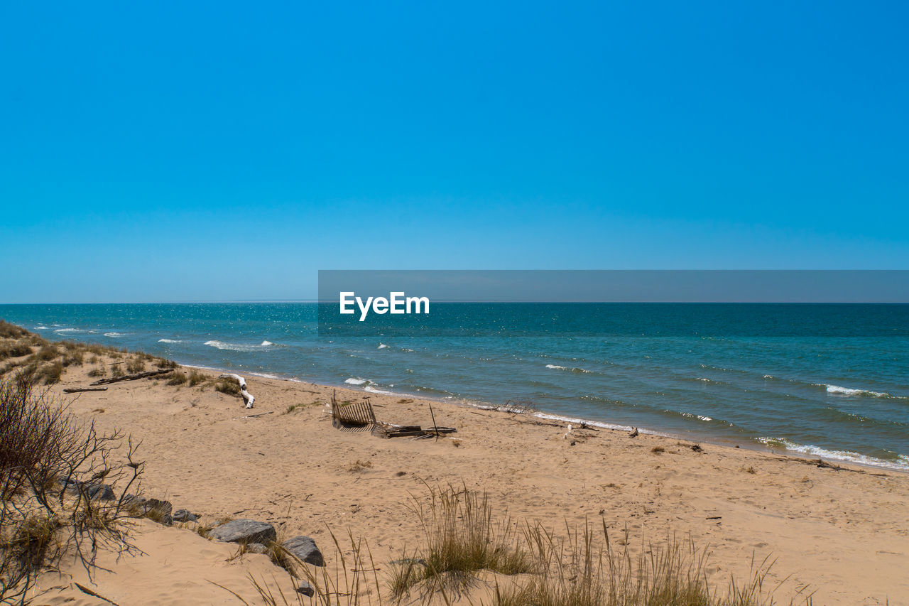 Scenic view of beach against clear blue sky