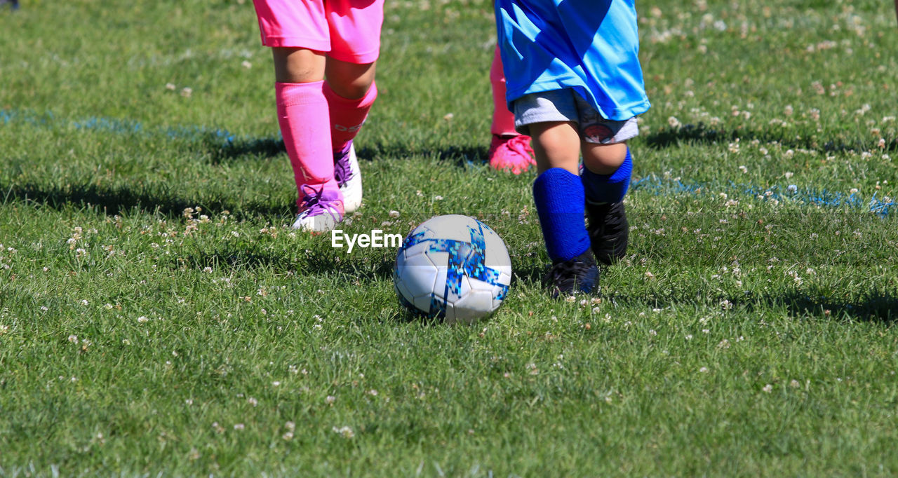 grass, soccer, team sport, sports, soccer ball, soccer player, ball, sports equipment, soccer field, athlete, child, soccer uniform, football player, sports clothing, childhood, sports uniform, low section, plant, clothing, human leg, nature, player, kicking, kids' soccer, motion, day, men, outdoors, field, playing field, exercising, competition, green, lifestyles, ball game, football, two people, leisure activity, soccer shoe, lawn, running