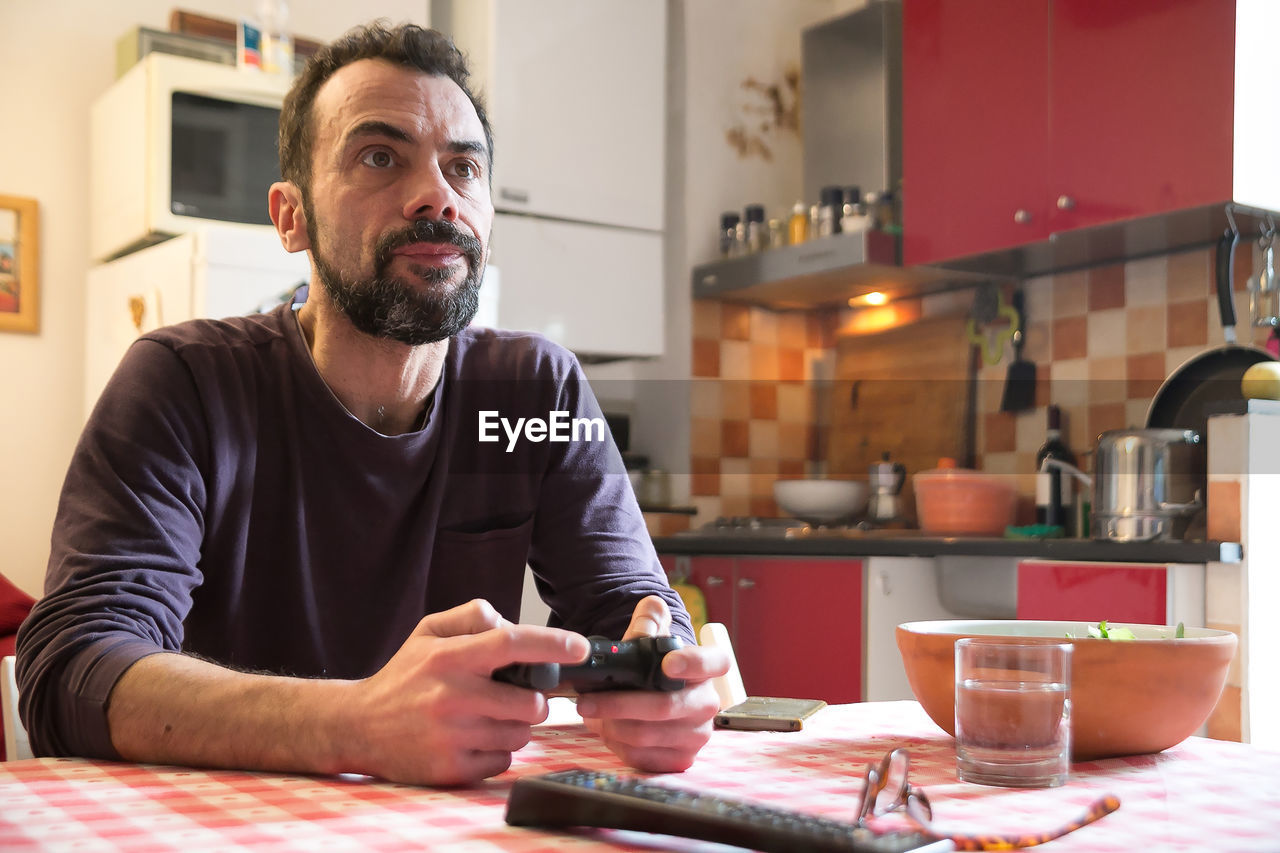 Man holding gaming console and sitting on table