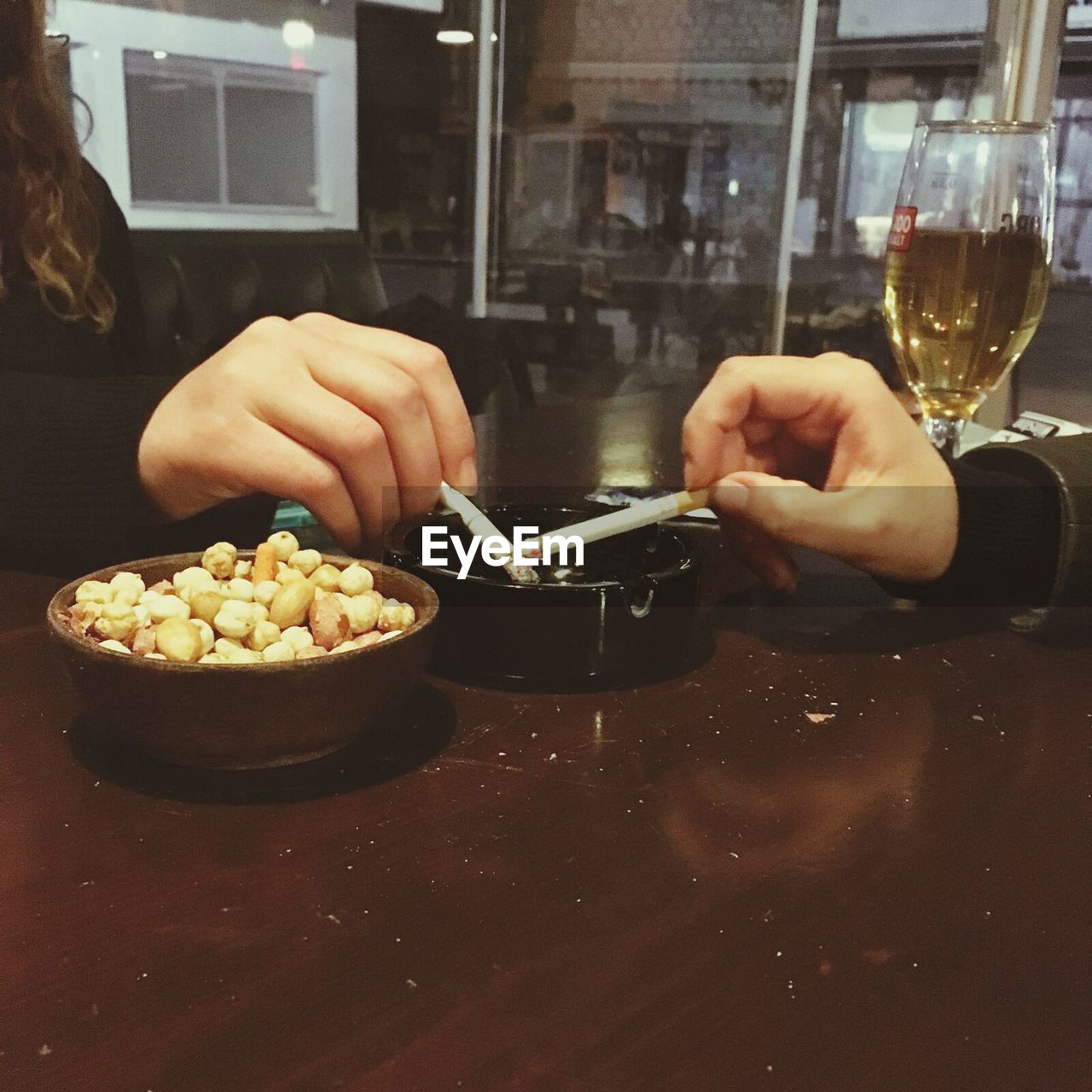 Cropped image of women holding cigarette on ashtray