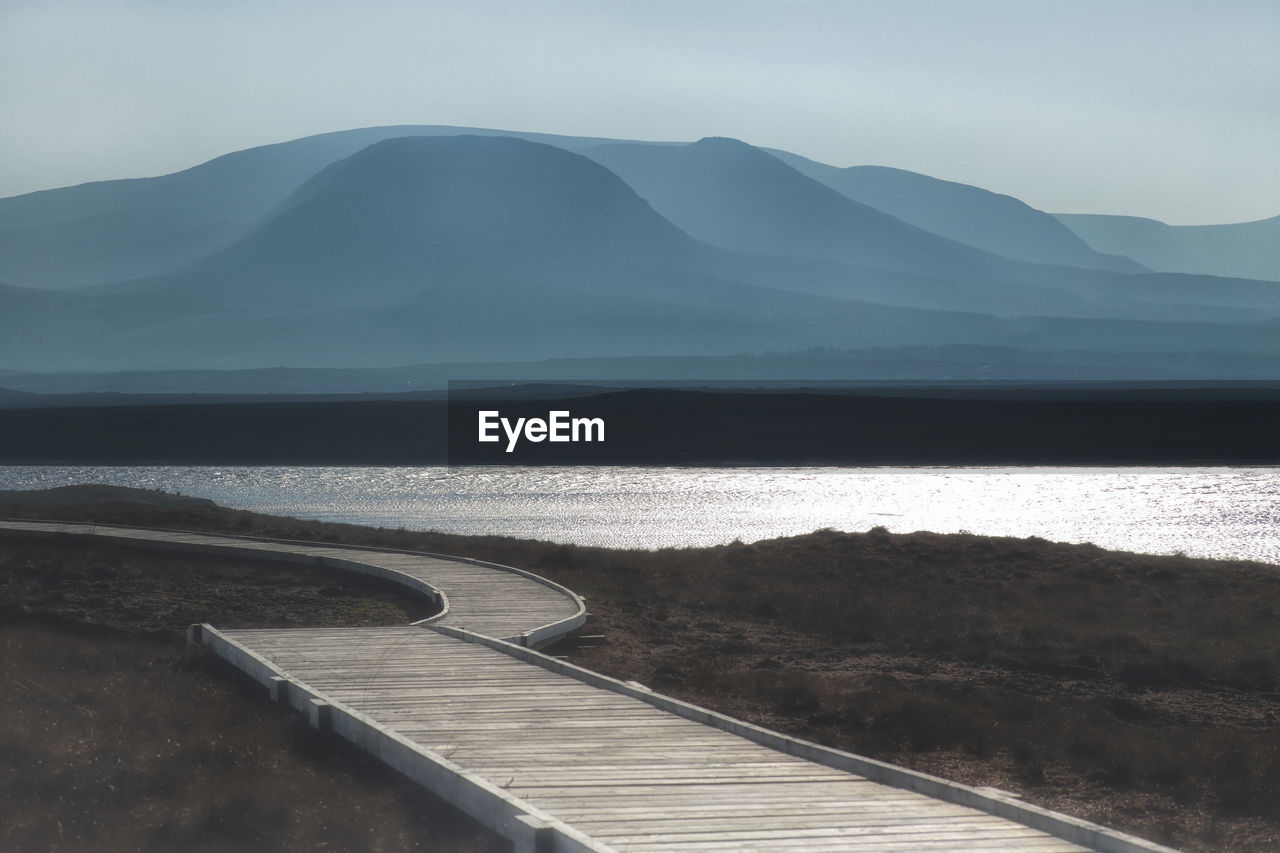 Scenic view of sea and mountains against sky