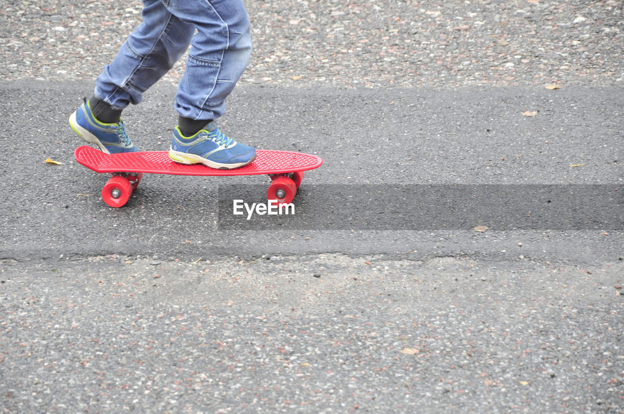 Low section of boy skateboarding on road