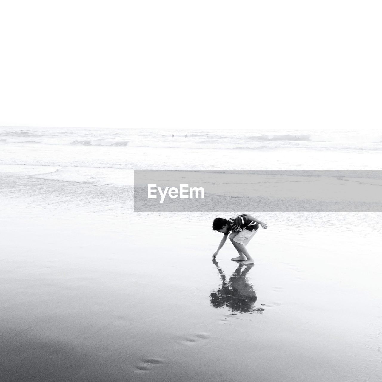 Boy touching sand at beach