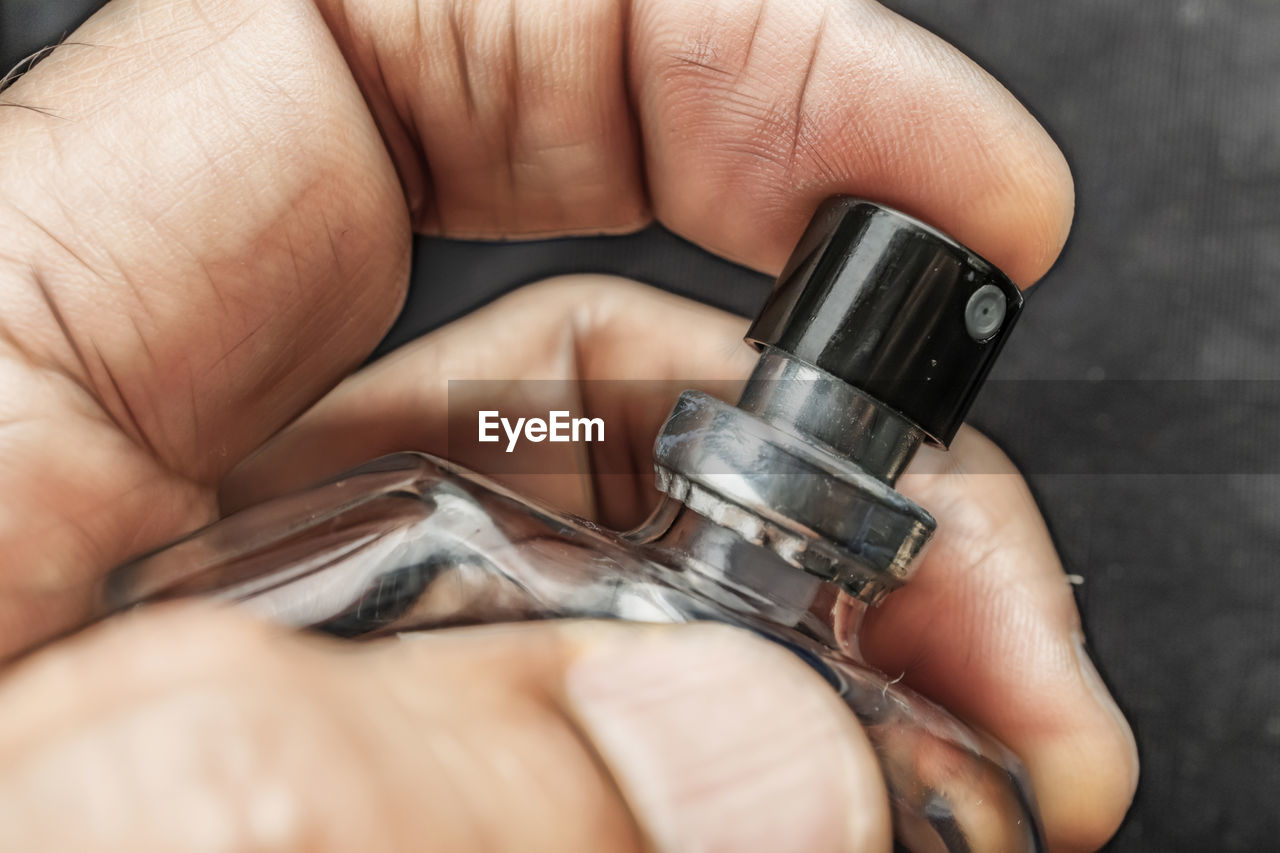 Cropped hand of man holding perfume sprayer