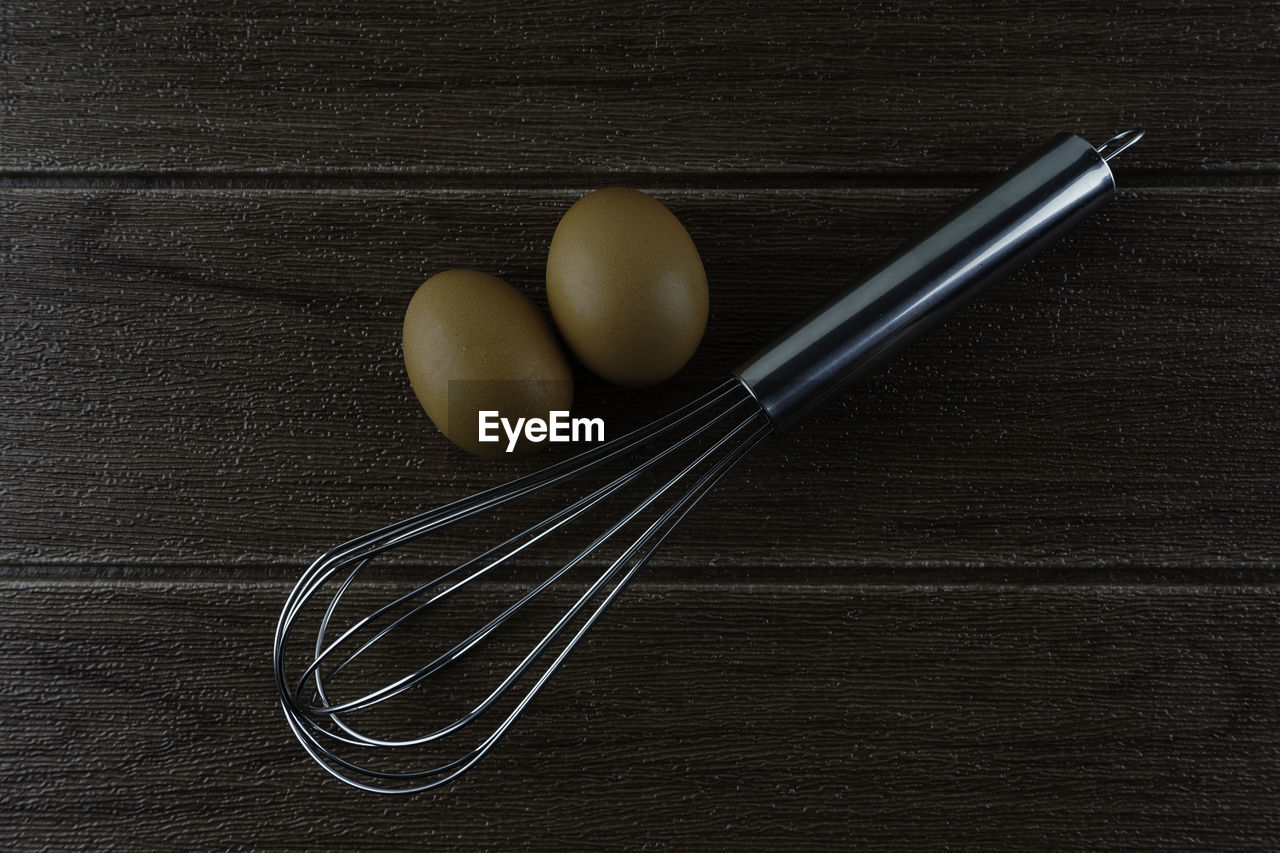 The whisk and eggs on a wooden table