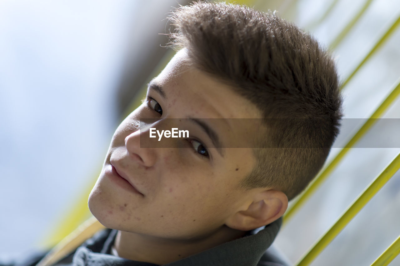 Close-up portrait of teenage boy against railing