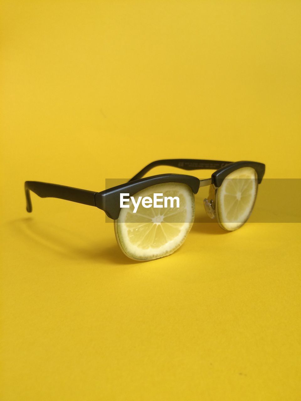 Eyeglasses made by lemon slices against yellow background