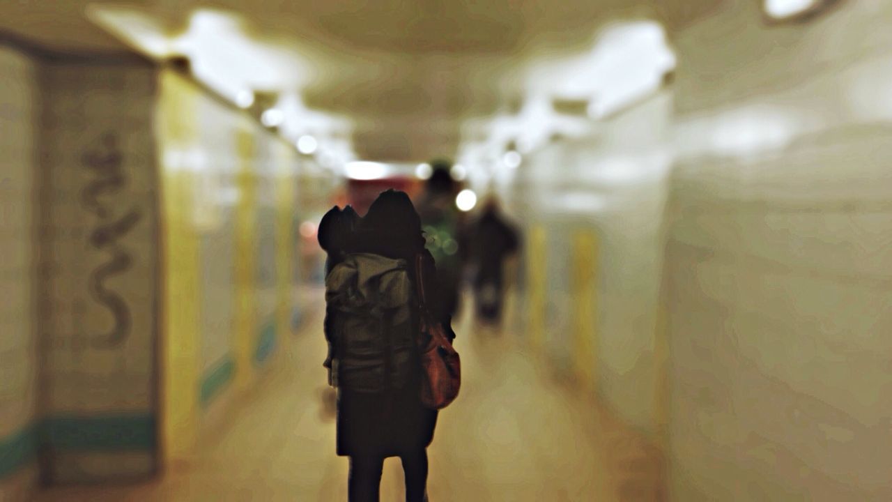 Rear view of woman with backpack walking in underground walkway