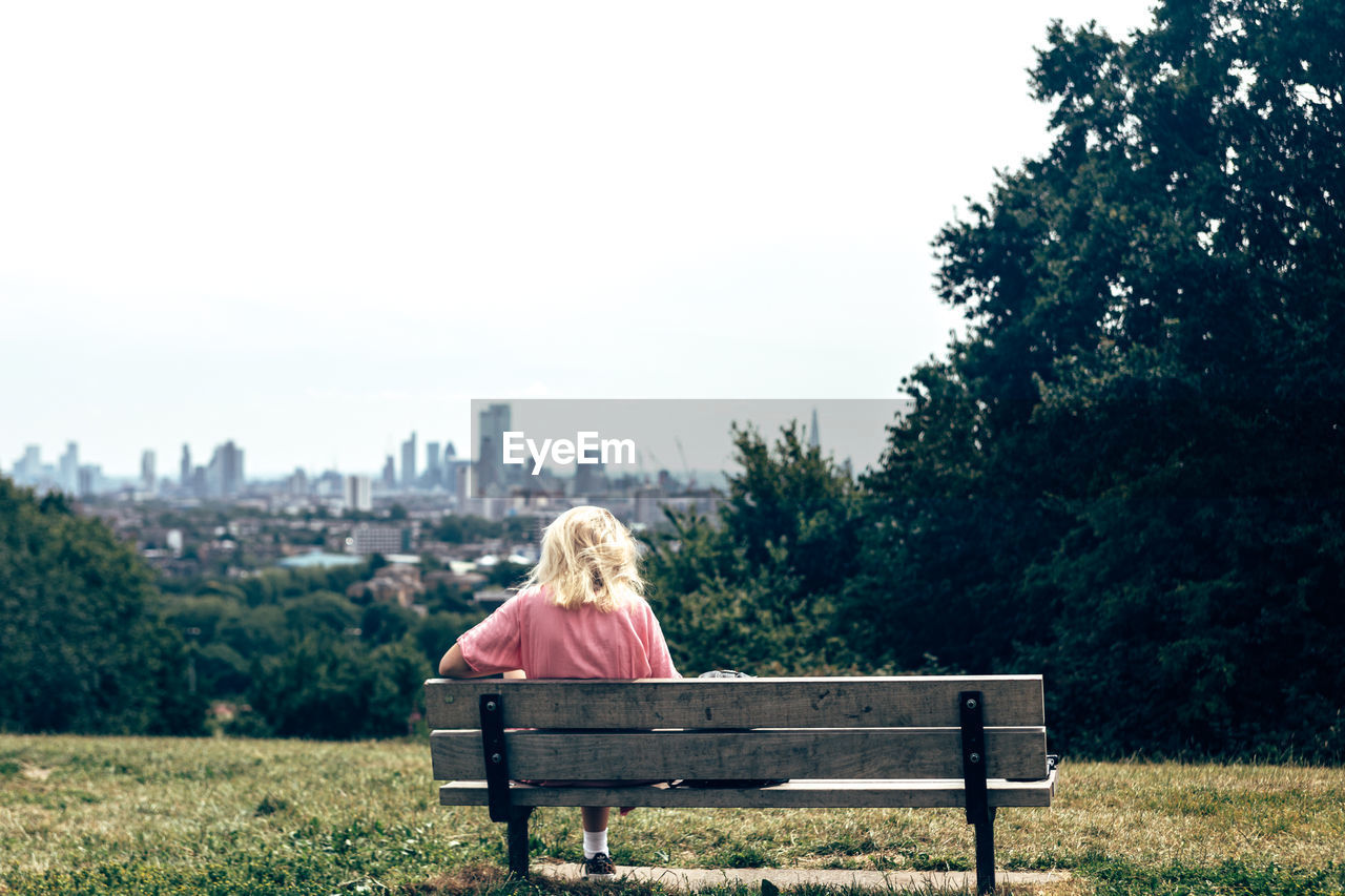 Rear view of woman sitting on bench at park