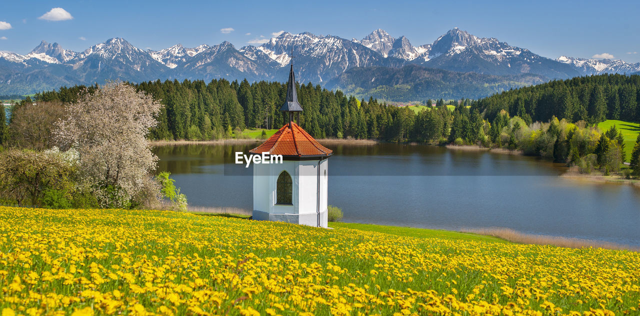 Panoramic landscape with chapel, mountains and meadow at springtime