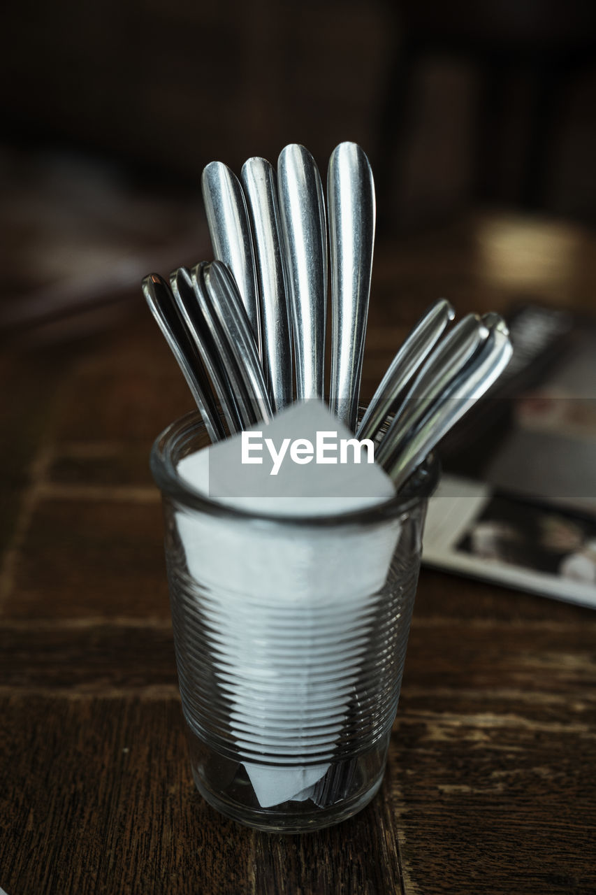 Close-up of spoons with tissue paper in glass on table