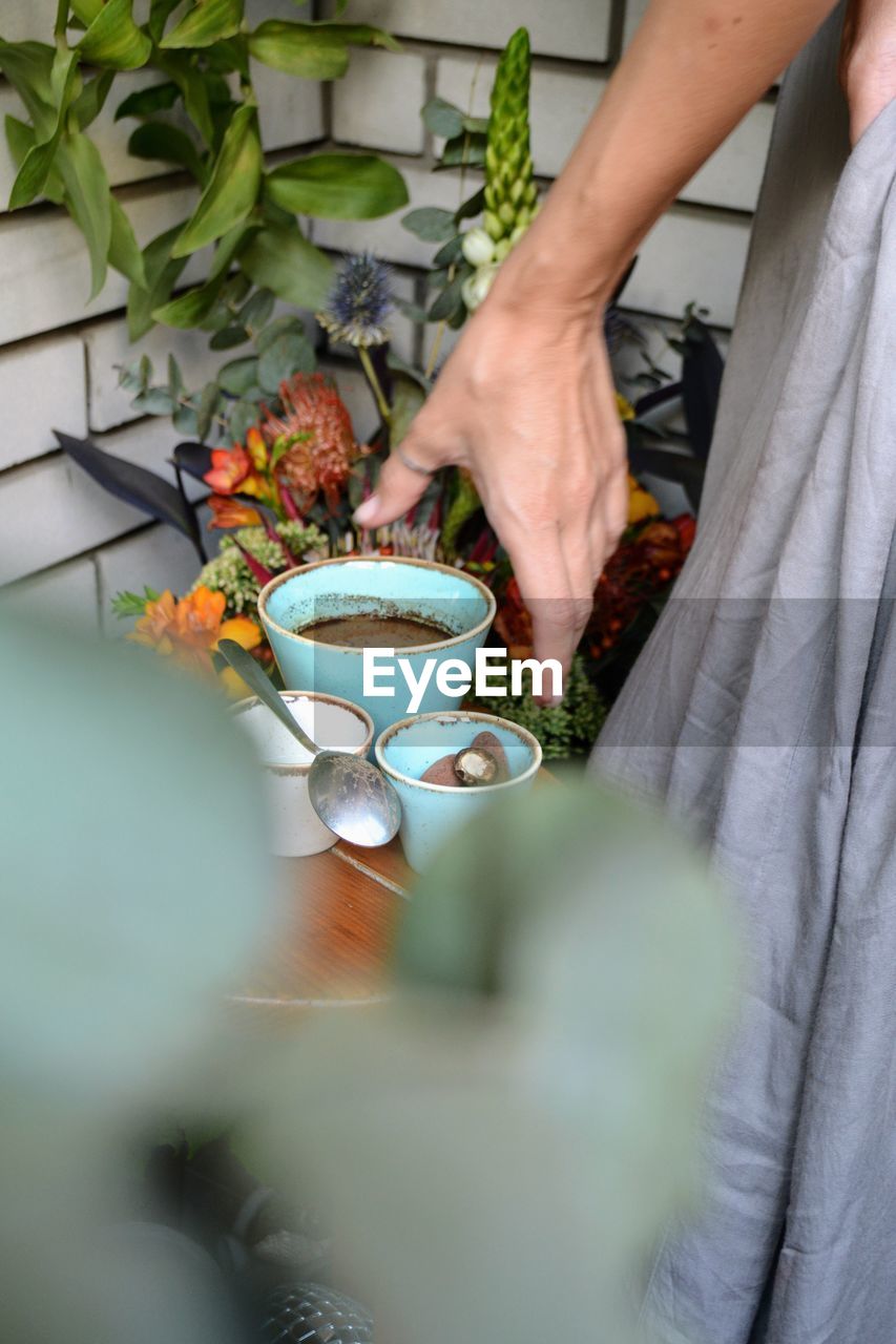 MIDSECTION OF MAN HOLDING COFFEE CUP WITH TEA