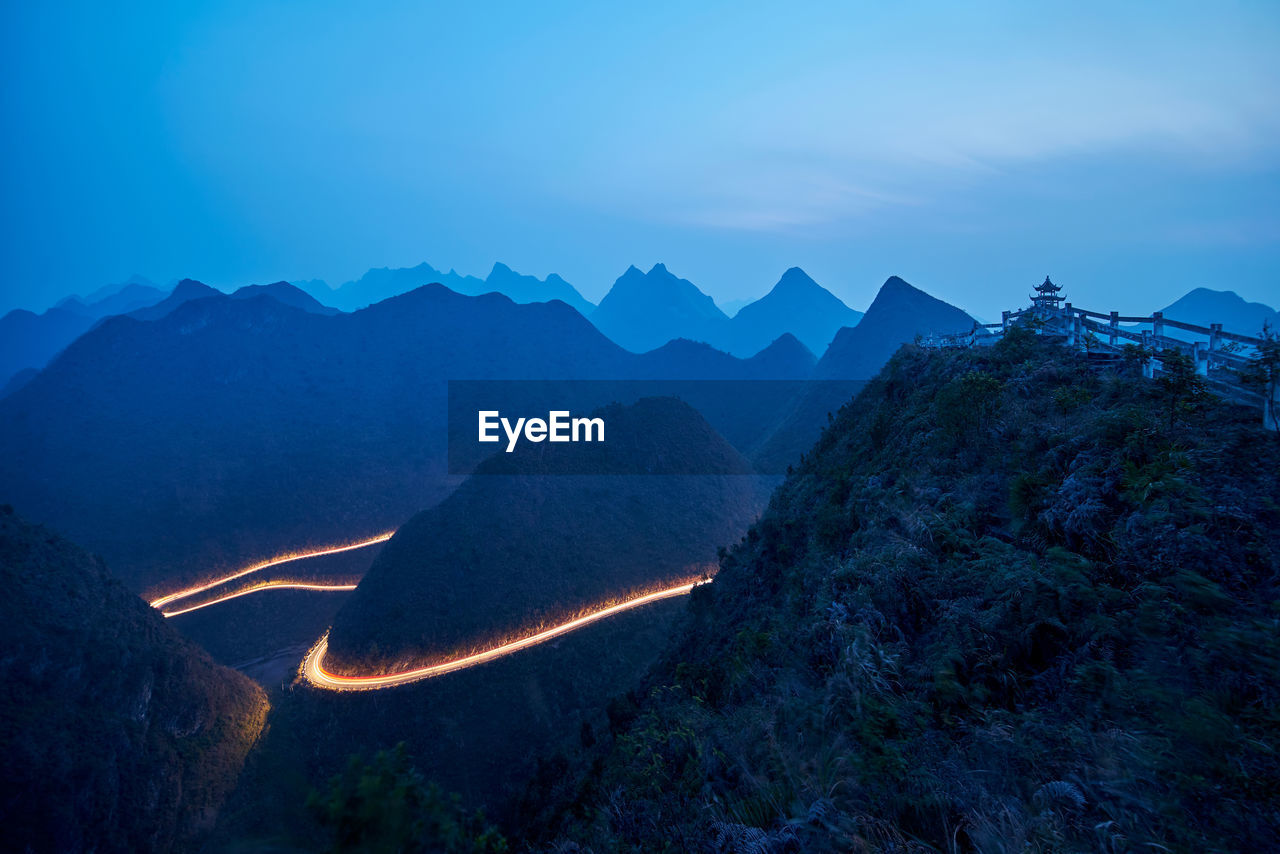 Aerial view of illuminated mountains against blue sky