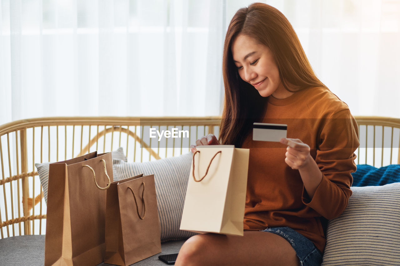 young woman using digital tablet while sitting on sofa