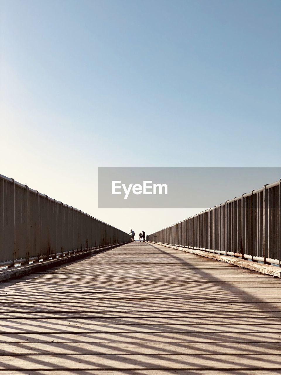 Man on railing against clear blue sky