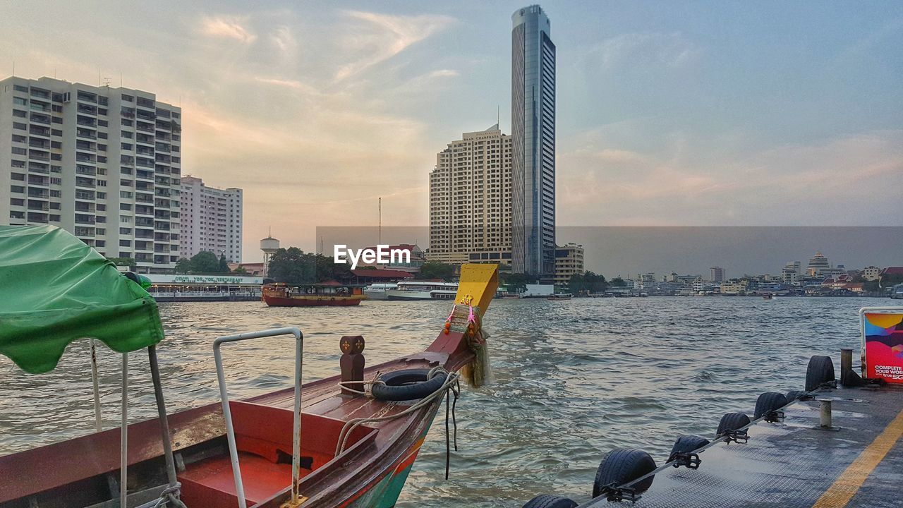 BUILDINGS BY RIVER AGAINST SKY DURING SUNSET