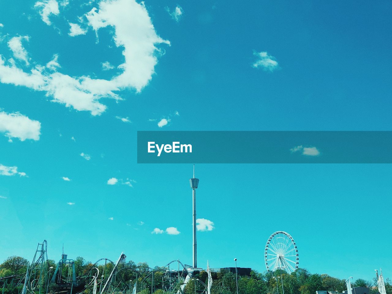 LOW ANGLE VIEW OF AMUSEMENT PARK AGAINST BLUE SKY