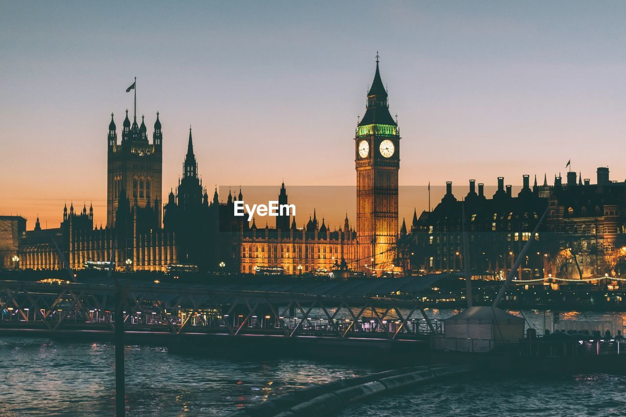 Illuminated big ben and parliament building in front of river thames