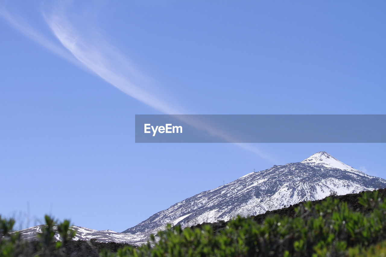 Low angle view of snowcapped mountain against blue sky