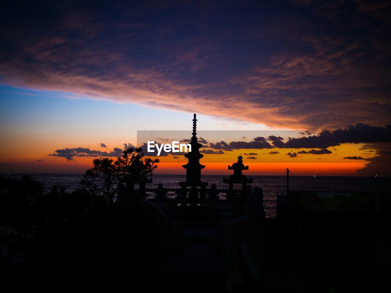 Silhouette haedong yonggung temple by sea against cloudy sky at sunrise