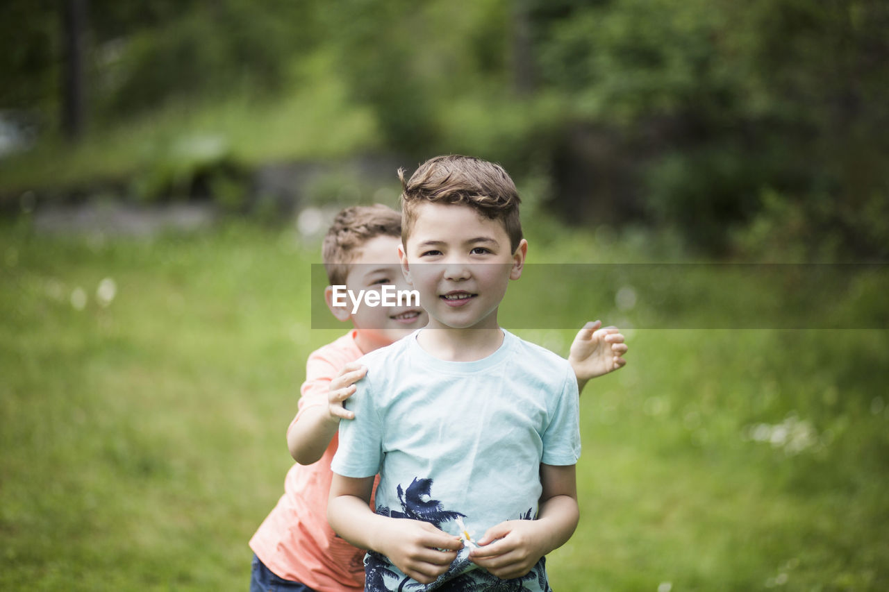 Portrait of boy with playful brother standing in back yard