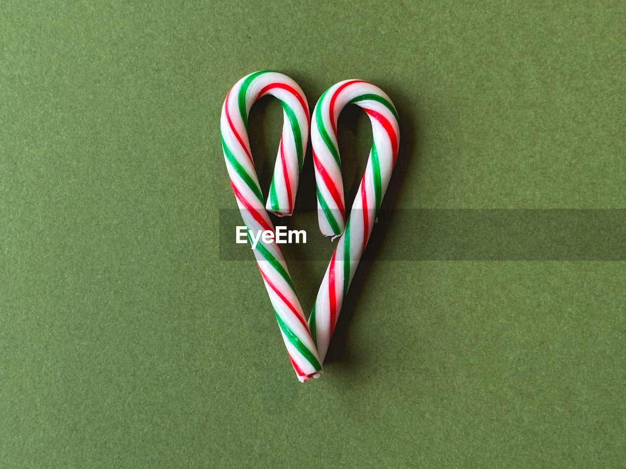 heart shape, sweet food, sweet, love, candy, positive emotion, emotion, food and drink, green, no people, food, confectionery, heart, studio shot, high angle view, candy cane, directly above, valentine's day, red, indoors, unhealthy eating, still life, multi colored, dessert, copy space, striped, colored background, green background, lollipop, close-up