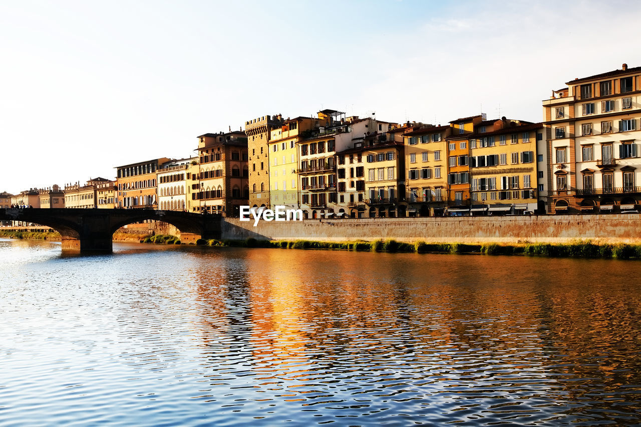 Ponte santa trinita over arno river by buildings at tuscany against clear sky