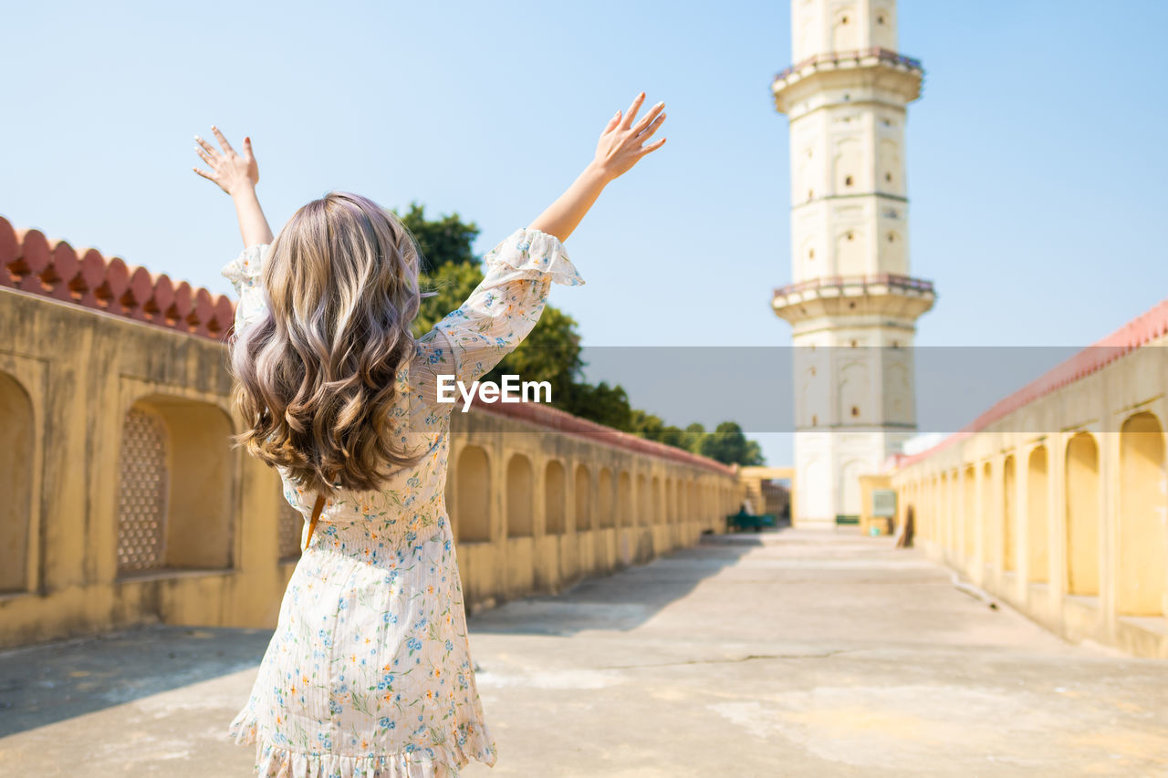 REAR VIEW OF WOMAN STANDING AT HISTORIC BUILDING