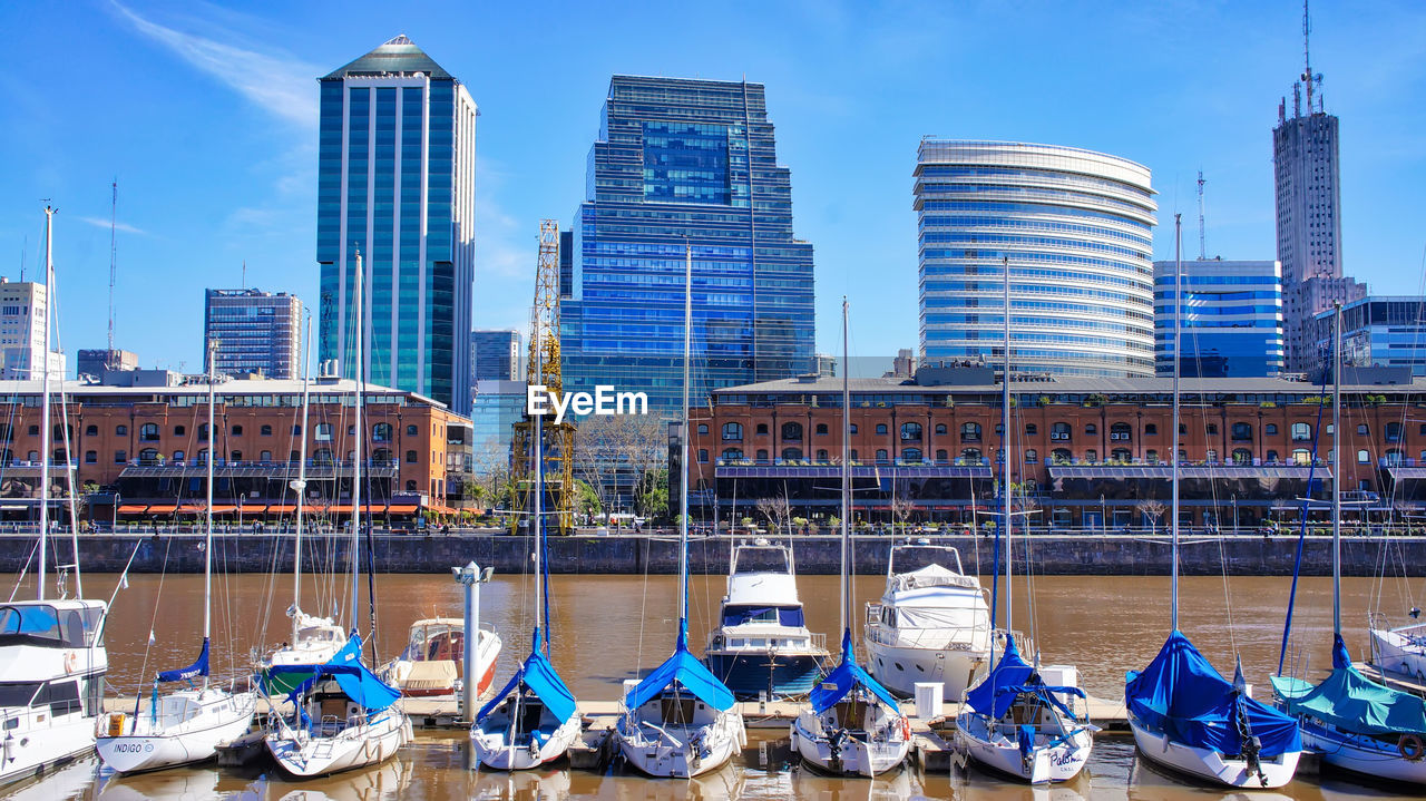 SAILBOATS MOORED IN CITY AGAINST BUILDINGS