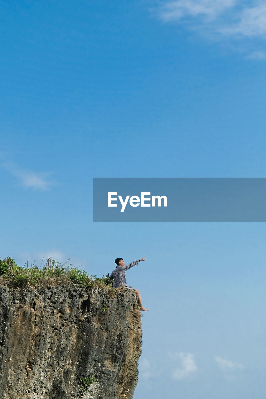 LOW ANGLE VIEW OF MAN ON ROCK