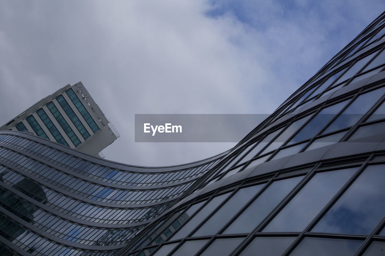 LOW ANGLE VIEW OF MODERN GLASS BUILDING AGAINST SKY