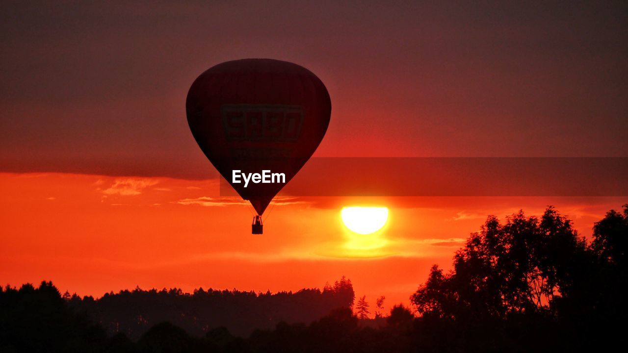 SILHOUETTE HOT AIR BALLOON AGAINST SKY AT SUNSET