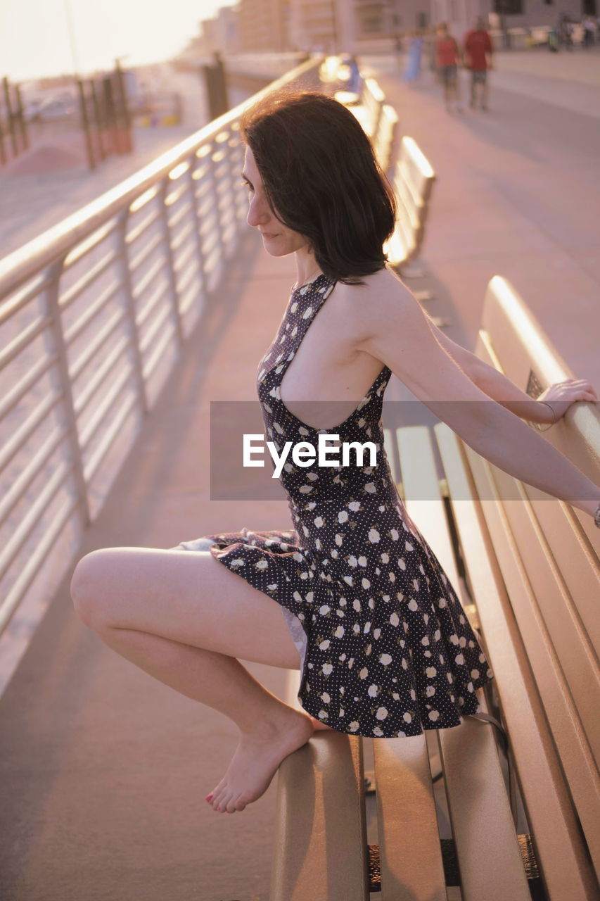 Side view of woman sitting on bench