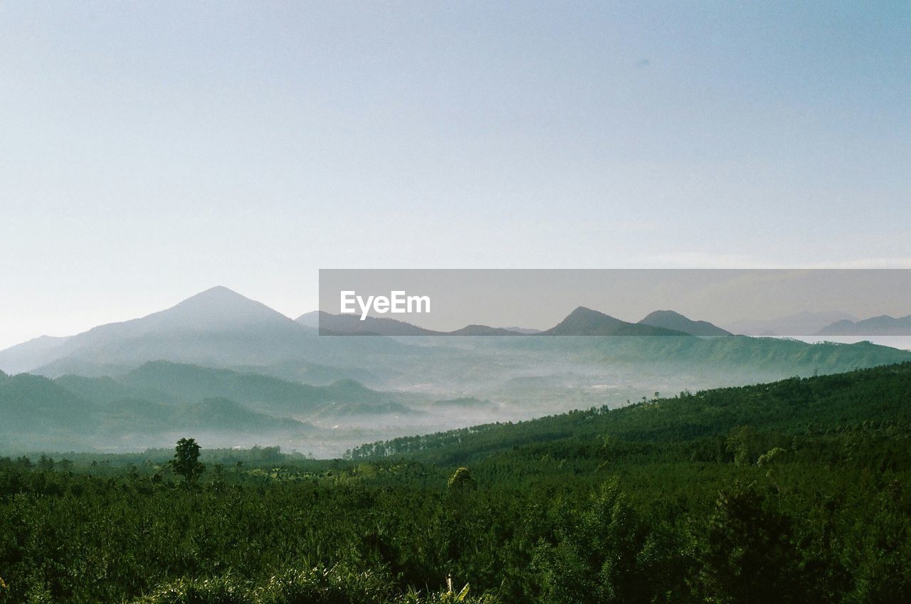 Scenic view of mountain range against sky in foggy weather