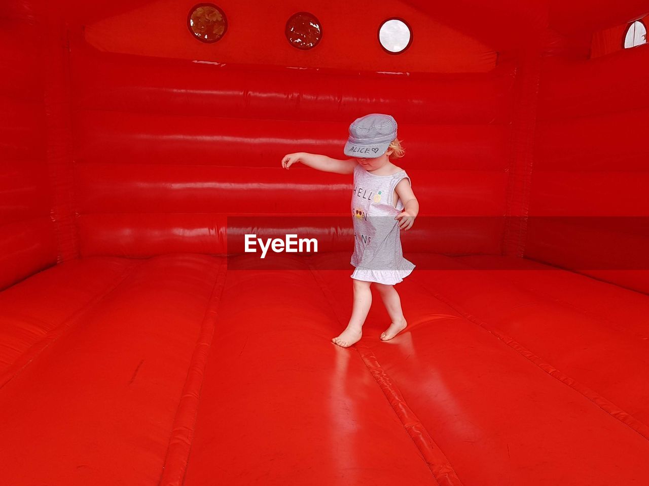 Full length of girl playing on red bouncy castle