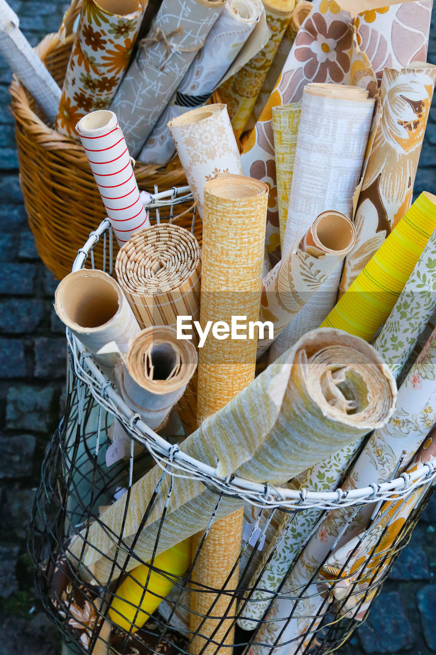 High angle view of rolled up wallpapers in basket for sale