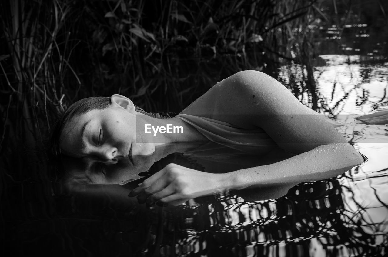 Close-up of young woman sleeping in pond