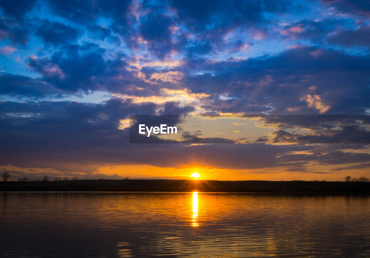 Scenic view of sea against dramatic sky during sunset