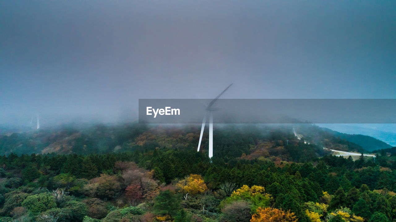 Wind turbines on landscape against sky
