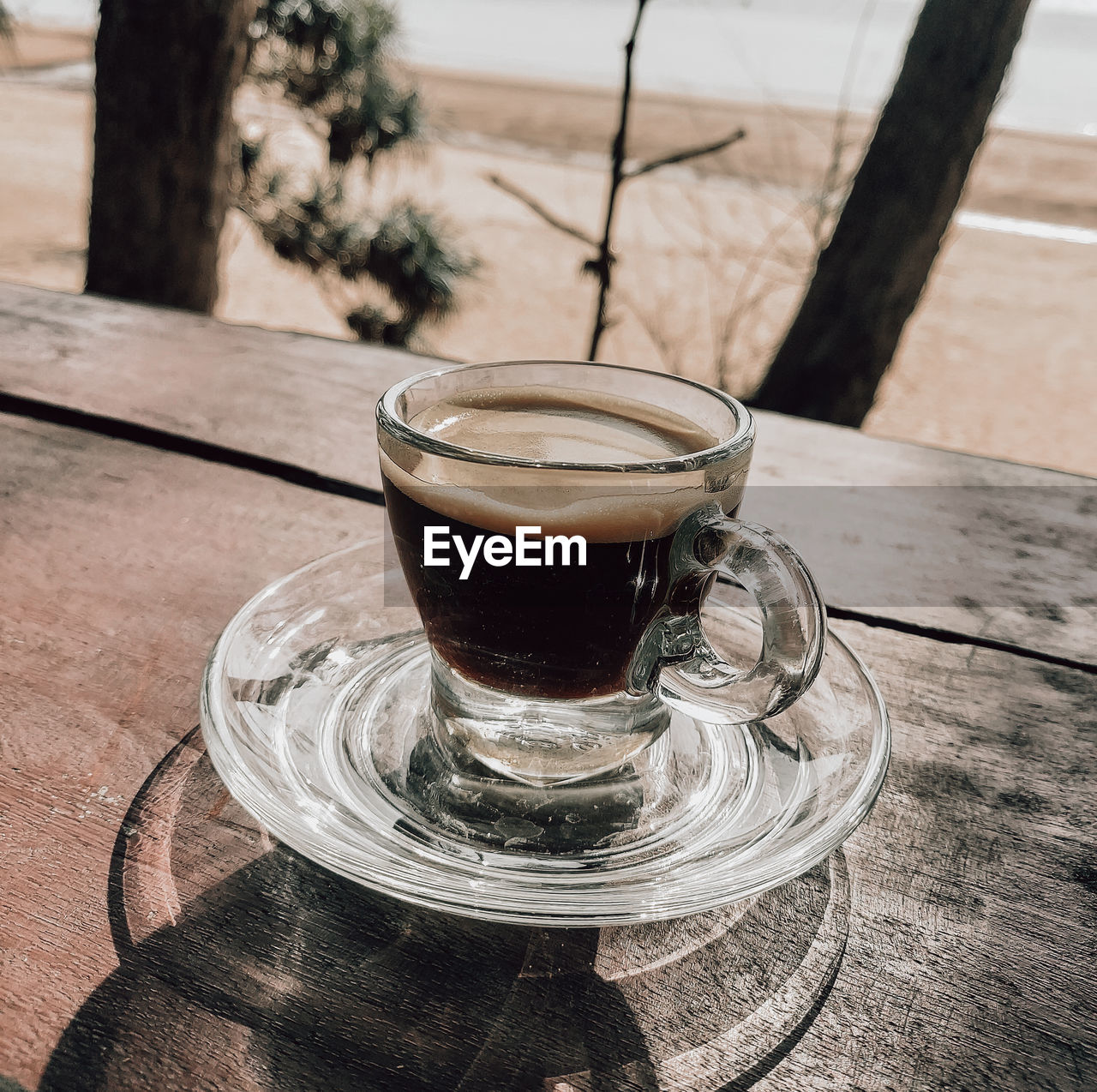 CLOSE-UP OF COFFEE CUP ON GLASS TABLE