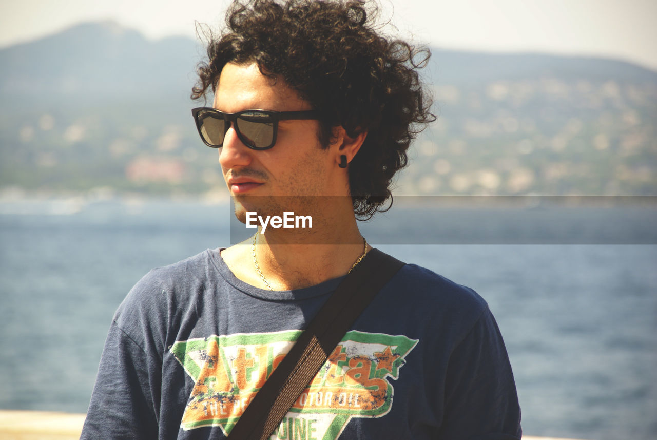 Young man wearing sunglasses against sea