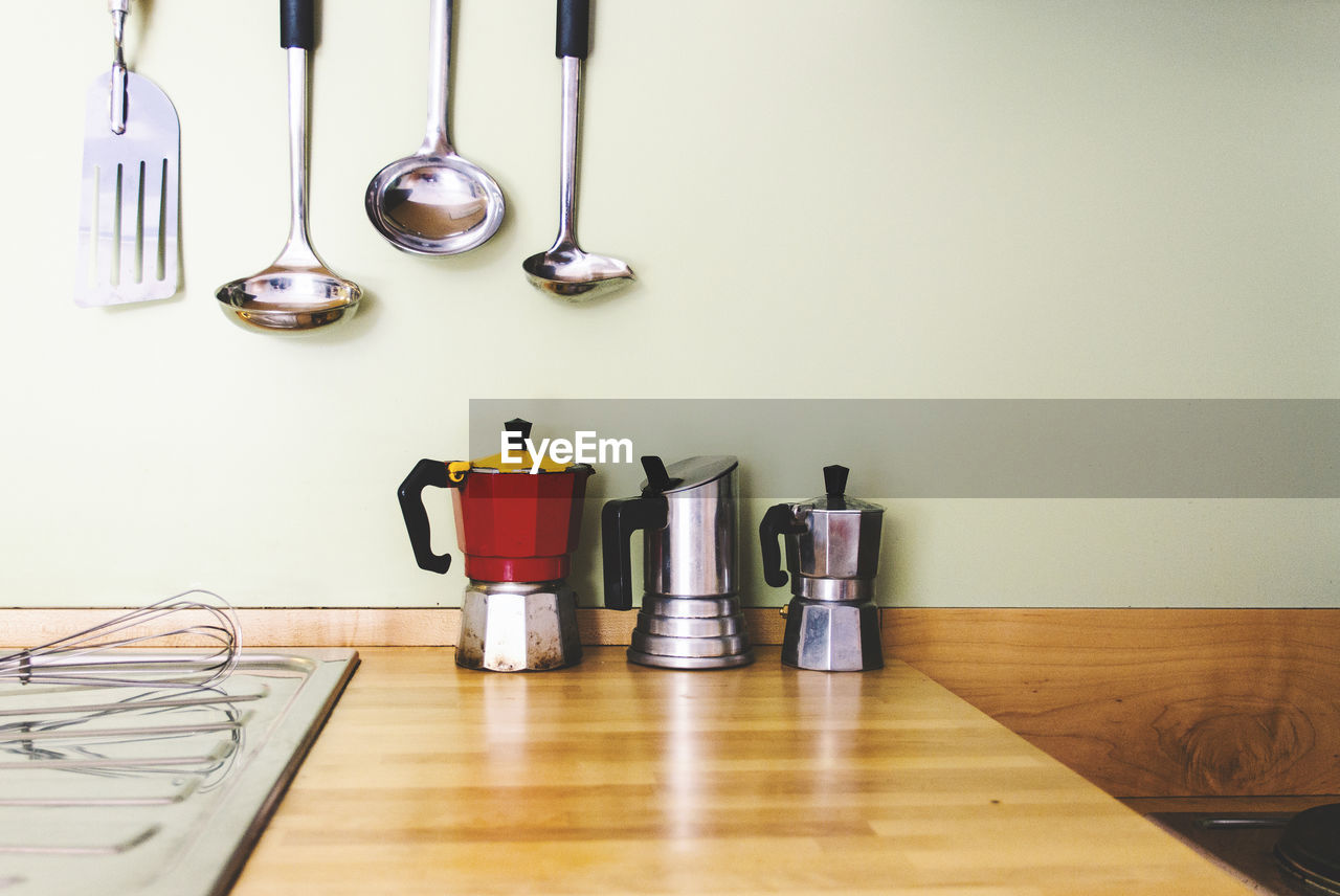 Coffee makers on table by utensils in kitchen