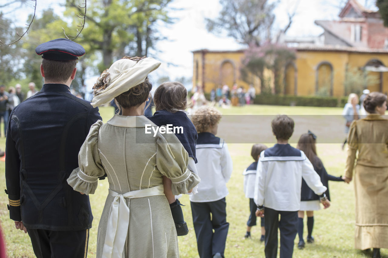 REAR VIEW OF PEOPLE WALKING IN FRONT OF AN ANIMAL