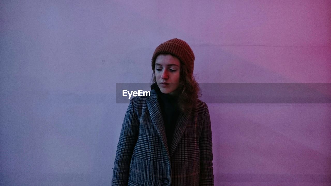 Thoughtful woman standing against wall